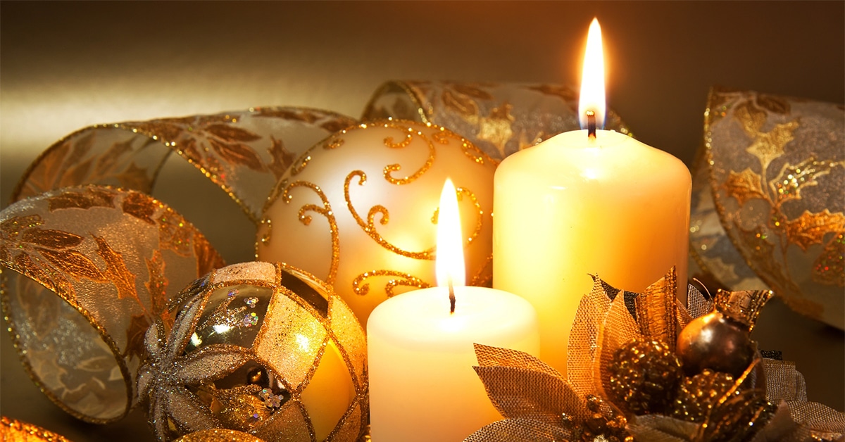 This image showcases a festive Christmas decoration theme, featuring lit candles, golden ornaments, and decorative ribbons with a glittery design. It conveys a warm, elegant holiday ambiance, suitable for inspiring Christmas decor ideas. This could be used to illustrate or complement tips for decorating a garage door or other areas safely during the holiday season.