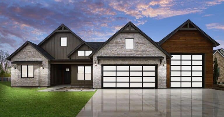 Modern farmhouse exterior at dusk with stone siding and three glass-panel garage doors.
